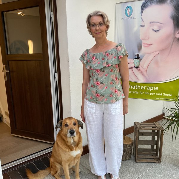 Inhaberin Monika Ellinger-Hoffmann vor dem Praxiseingang zusammen mit ihrem Hund Chico.